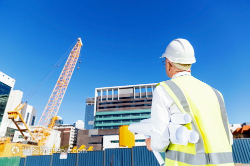 建筑工地的工程師建設者工程師建筑工人施工場景穿著帶藍圖的安全背心